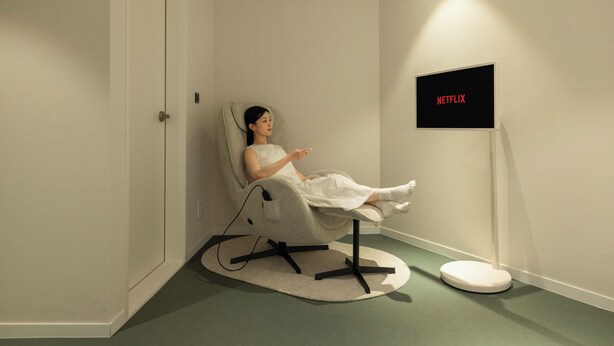 A room with a reclining chair, a television, and a wall-mounted sign.