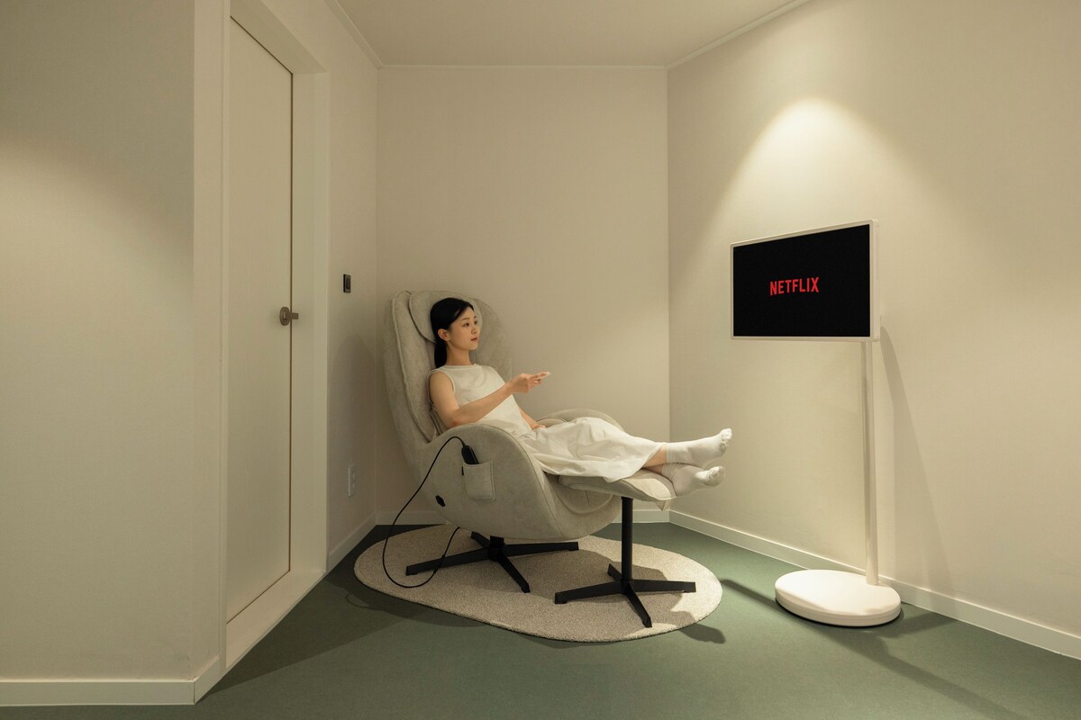 Una habitación con una silla reclinable, un televisor y un cartel en la pared.