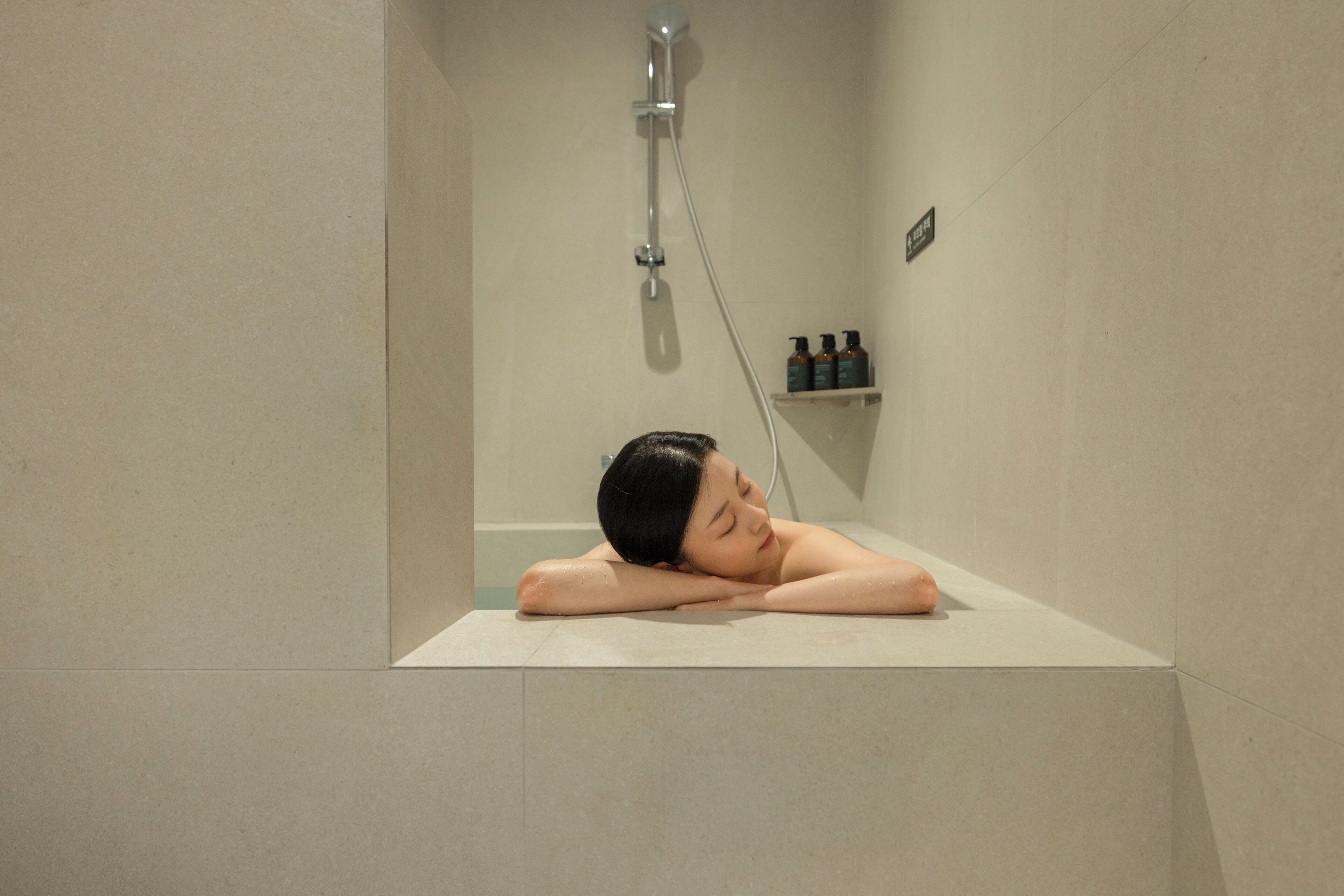 Una persona descansando en una bañera con un cabezal de ducha encima.