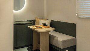 Una habitación pequeña con una cama, una mesita con bandeja, un cuenco y una almohada.