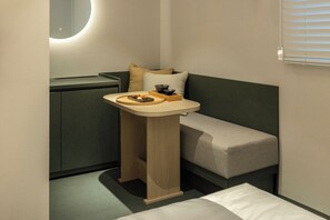 A compact room with a bed, a small table with a tray, a bowl, and a pillow.
