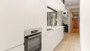 A modern kitchen with a built-in oven, a large window, and a view of the hallway. - Modern Designer Terrace Next to Surry Hills (Redfern)