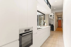 Eine moderne Küche mit Backofen, großem Fenster und Blick auf das Treppenhaus.