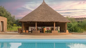 A thatched-roof pavilion with a pool in front. - Hampi's Feathers Resort (Koppal)