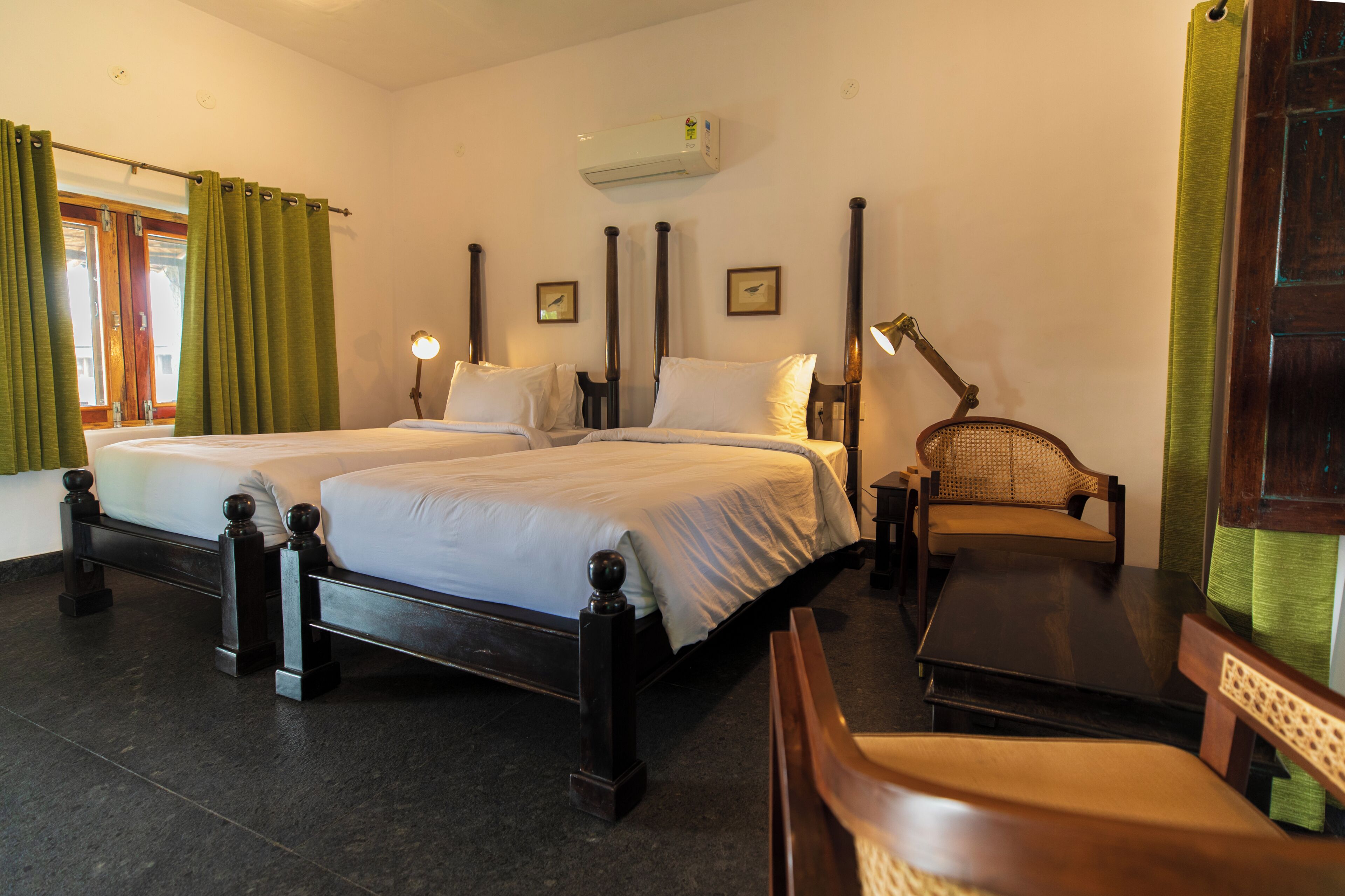 A hotel room with two beds, a desk, a chair, and an air conditioning unit.