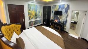 A hotel room with a large bed, a television, a painting, and a mirror. - King Luxury Hotel (Tu Liem)