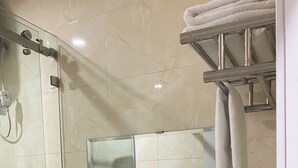 A bathroom with a glass shower enclosure, a sink with a vanity, a towel rack, and a hairdryer. - King Luxury Hotel (Tu Liem)