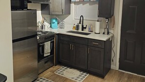 Une cuisine avec des meubles de couleur sombre, des appareils électroménagers en acier inoxydable, un évier et une fenêtre donnant sur un beau paysage.