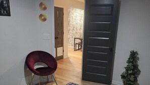 A room with a bed, a red chair, a potted plant, and a door leading to another room. - Stay in the Heart of Atlanta Comfortable, Stylish & Close to Everything (Atlanta)