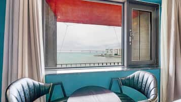 Una habitación con vistas a un puente y edificios al otro lado del agua, una ventana con persiana roja y dos sillones de cuero.