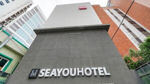 The exterior of the Seayou Hotel with a modern design, featuring a prominent sign and a small red object on the roof. - Busan Gwangalli SEAYOU HOTEL (Busan)
