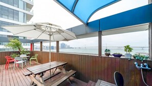 A deck with wooden furniture, a table, chairs, and a large umbrella. - Busan Gwangalli SEAYOU HOTEL (Busan)