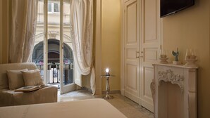Una camera d'albergo con un letto, un'area salotto con un divano, un tavolino con una lampada, una televisione a parete e un ampio armadio.