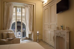Ein Hotelzimmer mit Bett, einer Sitzecke mit Sofa, einem kleinen Tisch mit Lampe, einem an der Wand befestigten Fernseher und einem großen Kleiderschrank.