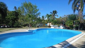 Uma piscina com água azul cristalina, rodeada por árvores e um céu limpo.