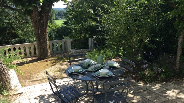 An outdoor dining area with a table set for four, surrounded by greenery and a stone wall. - The Sequoia... in the Countryside (Fondettes)