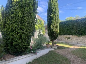 A residential garden with tall cypress trees, a stone wall, and a pathway. - The Sequoia... in the Countryside (Fondettes)