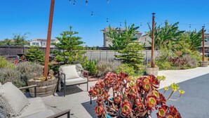 Eine Terrasse mit Gartenmöbeln, einem Blumentopf und Blick auf Wohnhäuser im Hintergrund.