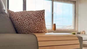 Ett modernt vardagsrum med en soffa, en kudde med leopardmönster och ett fönster med persienner.