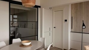 Ett modernt kök med ett matbord, stolar, en hängande lampa och ett träskåp.