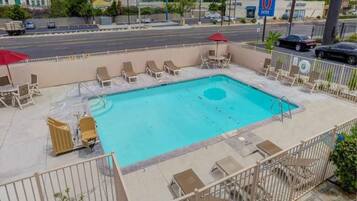 A swimming pool with lounge chairs, a lifeguard chair, and a fence.