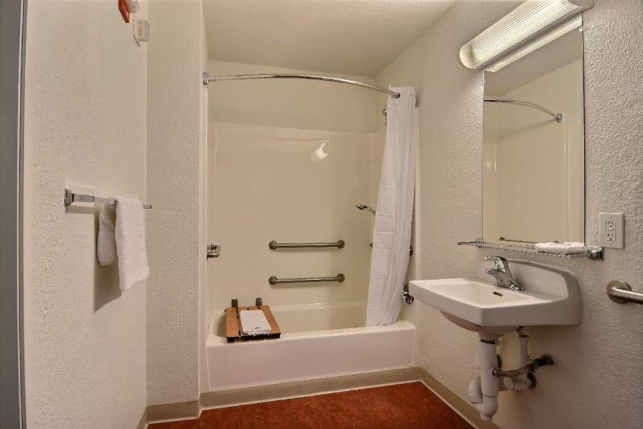 A bathroom with a shower, a sink, a mirror, and a towel rack.