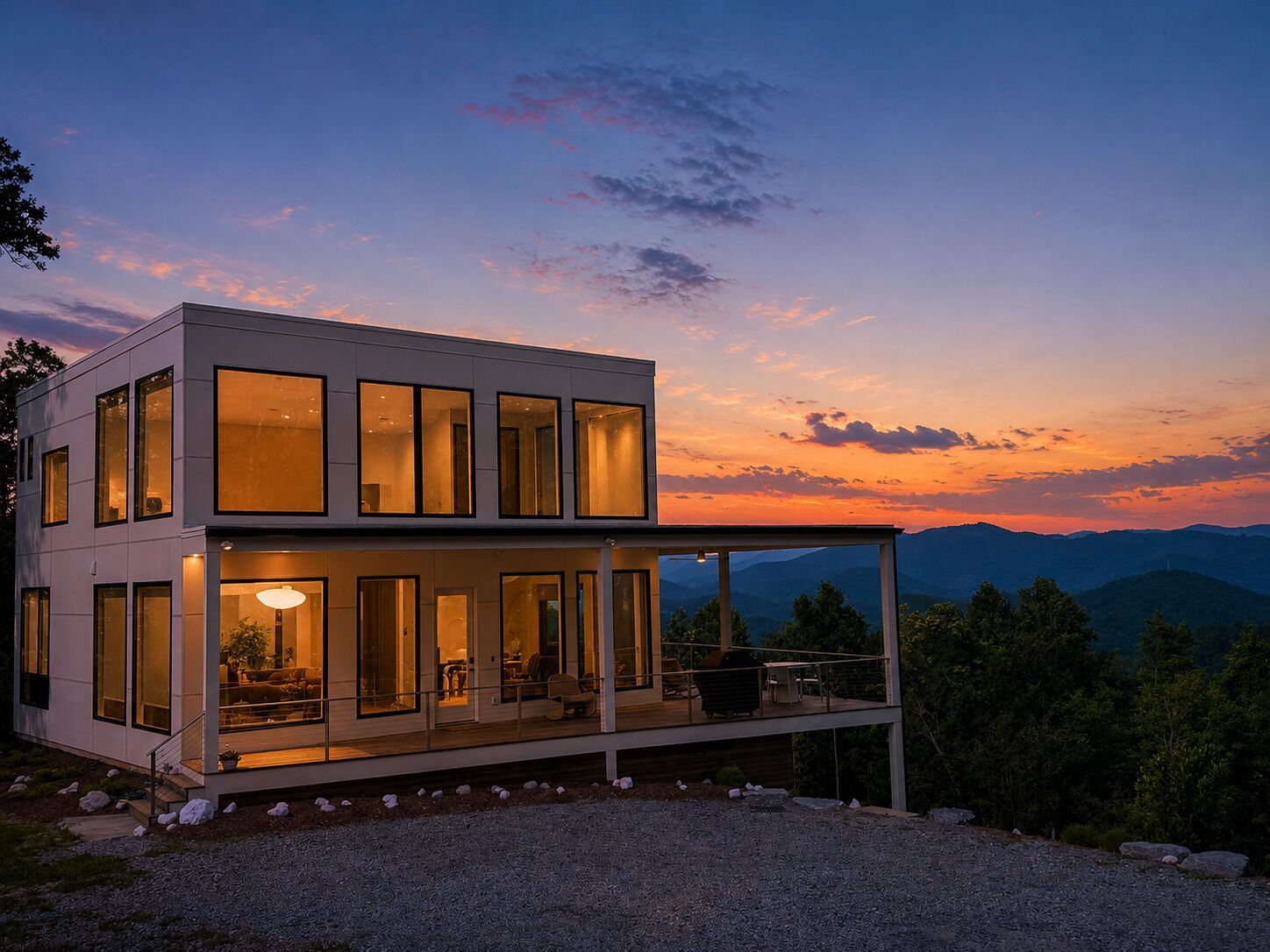 Ein modernes, zweistöckiges Haus mit großen Fenstern, einem Balkon und Bergblick.