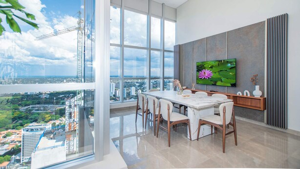 Un comedor moderno con un amplio ventanal, un televisor de pantalla plana y vistas a la ciudad.