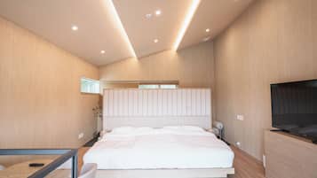 Ein modernes Schlafzimmer mit einem großen Bett, einem Fernseher und einem Schreibtisch mit Stuhl.