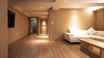 A modern interior with a wooden floor, a sofa, and a flat-screen TV mounted on the wall.