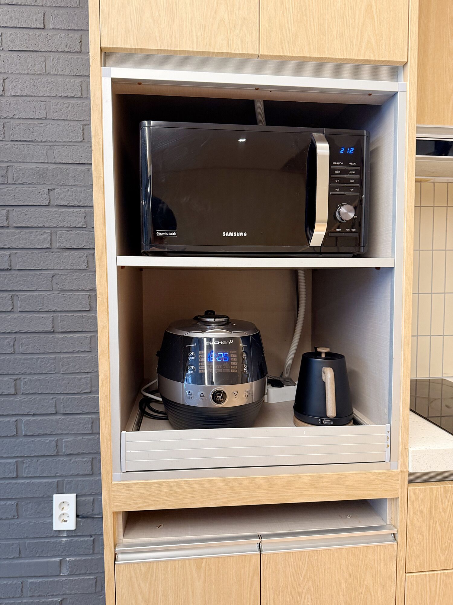 Een magnetron en koffiezetapparaat in een houten kast.