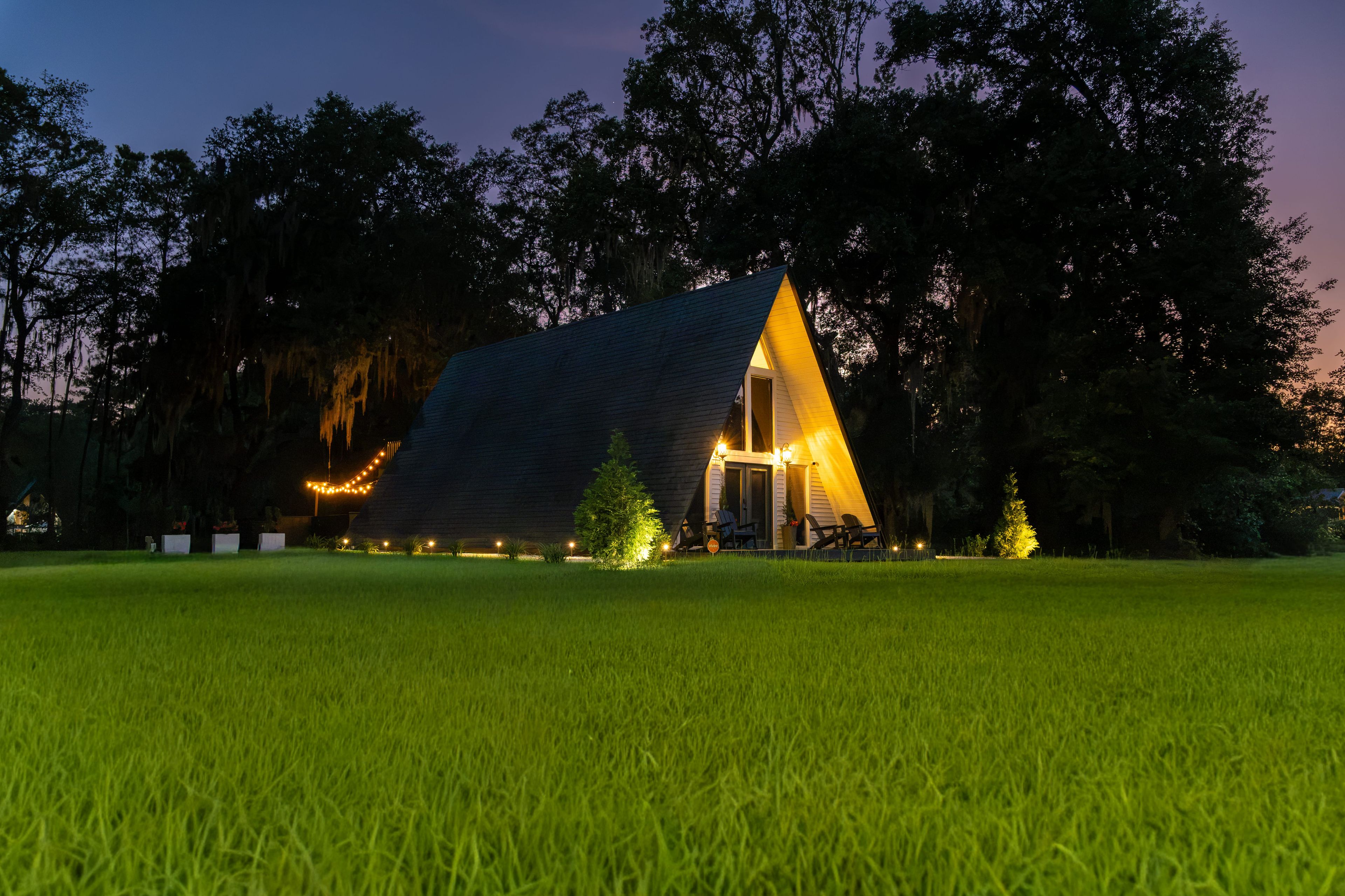 A triangular-shaped building with a sloped roof, surrounded by a well-maintained lawn and trees.