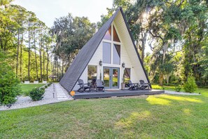A modern A-frame house with a deck, outdoor seating, and a garden. - Hot Tub, Grill & Fire Pit: Quiet Georgetown Escape (Savannah)