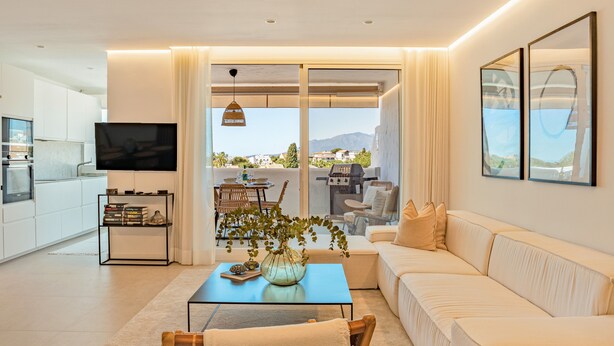 A modern living room with a sofa, a coffee table, a TV, and a balcony with a grill. - Apartment 'Alexy' with Sea Views, Wi-Fi, and Air Conditioning (Marbella)