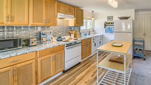 A kitchen with wooden cabinets, a microwave, a stove, and a small table with a basket. - Fire Pit, Private Dock! Lamoka Lake Retreat (Bradford)