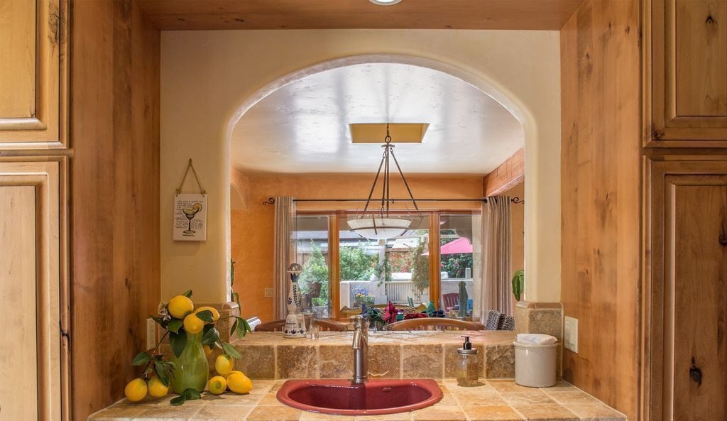 A kitchen with a central island, a sink, and a window with curtains.