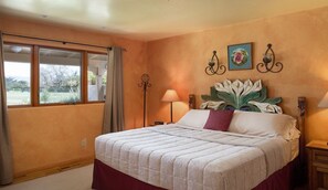 Een slaapkamer met een bed, een raam, een nachtkastje en een wandlamp.