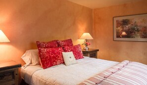 A bedroom with a bed, pillows, a nightstand, a lamp, and a painting on the wall. - Mi Casa - Monterey Home - Del Monte Golf Course Frontage (Monterey)