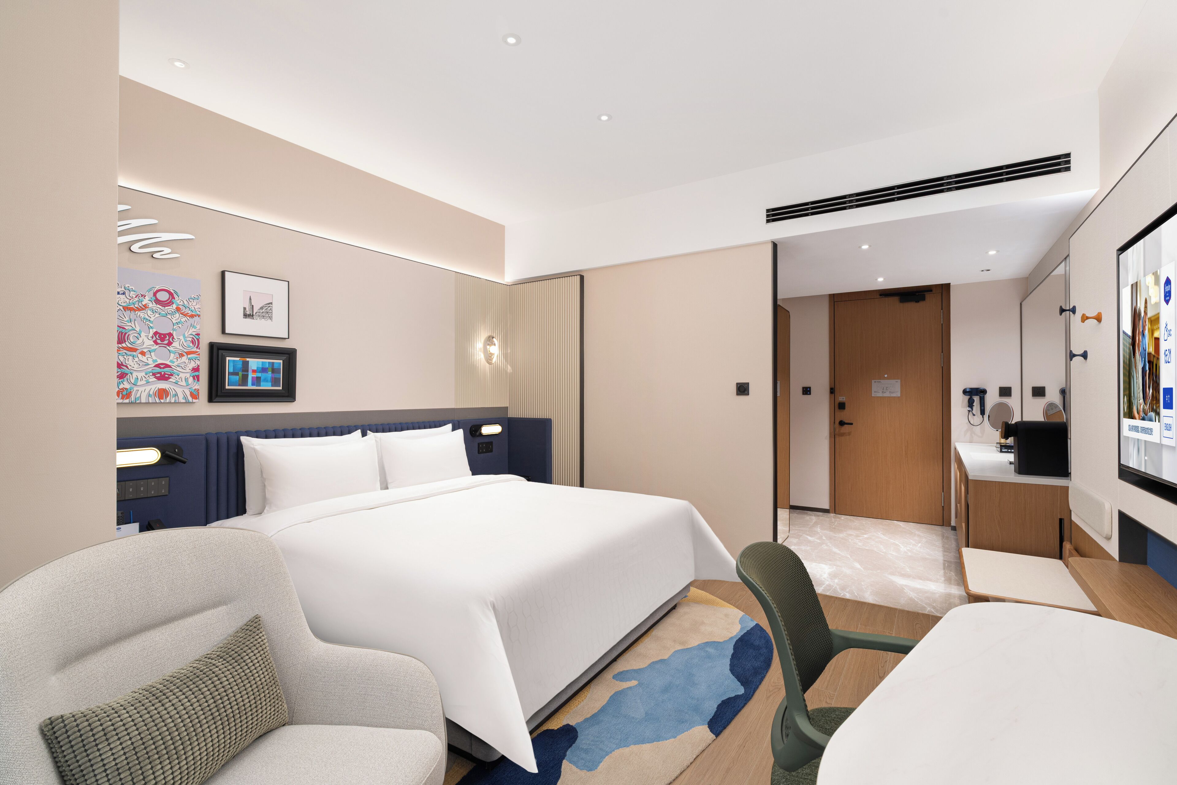 Habitación de hotel moderna con una cama grande, un escritorio, una silla y un baño visible a través de una puerta abierta.