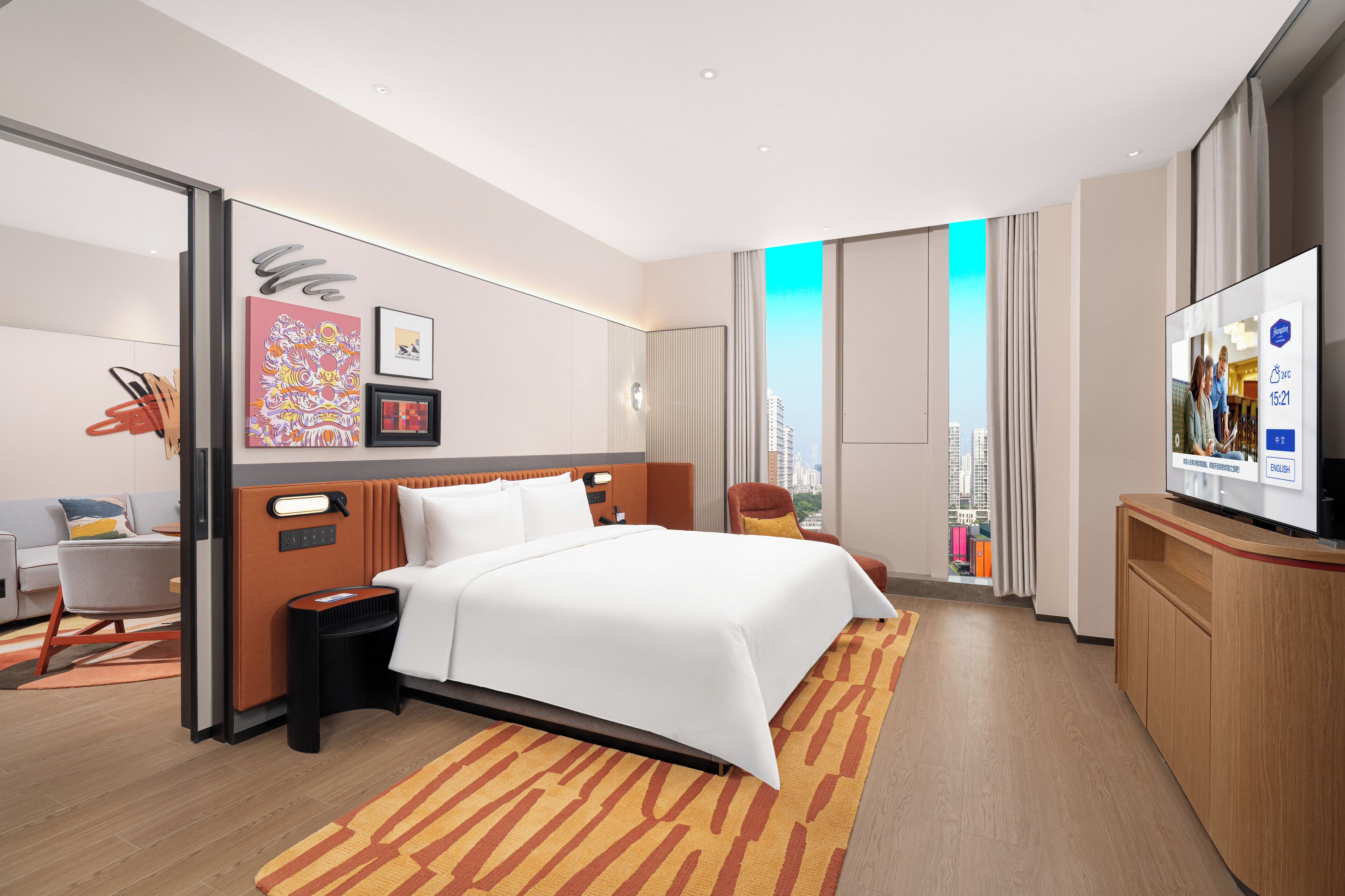 A modern hotel room with a large bed, a desk, a chair, and a television.