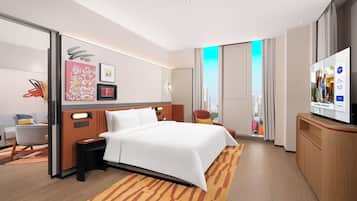 A modern hotel room with a large bed, a desk, a chair, and a television.