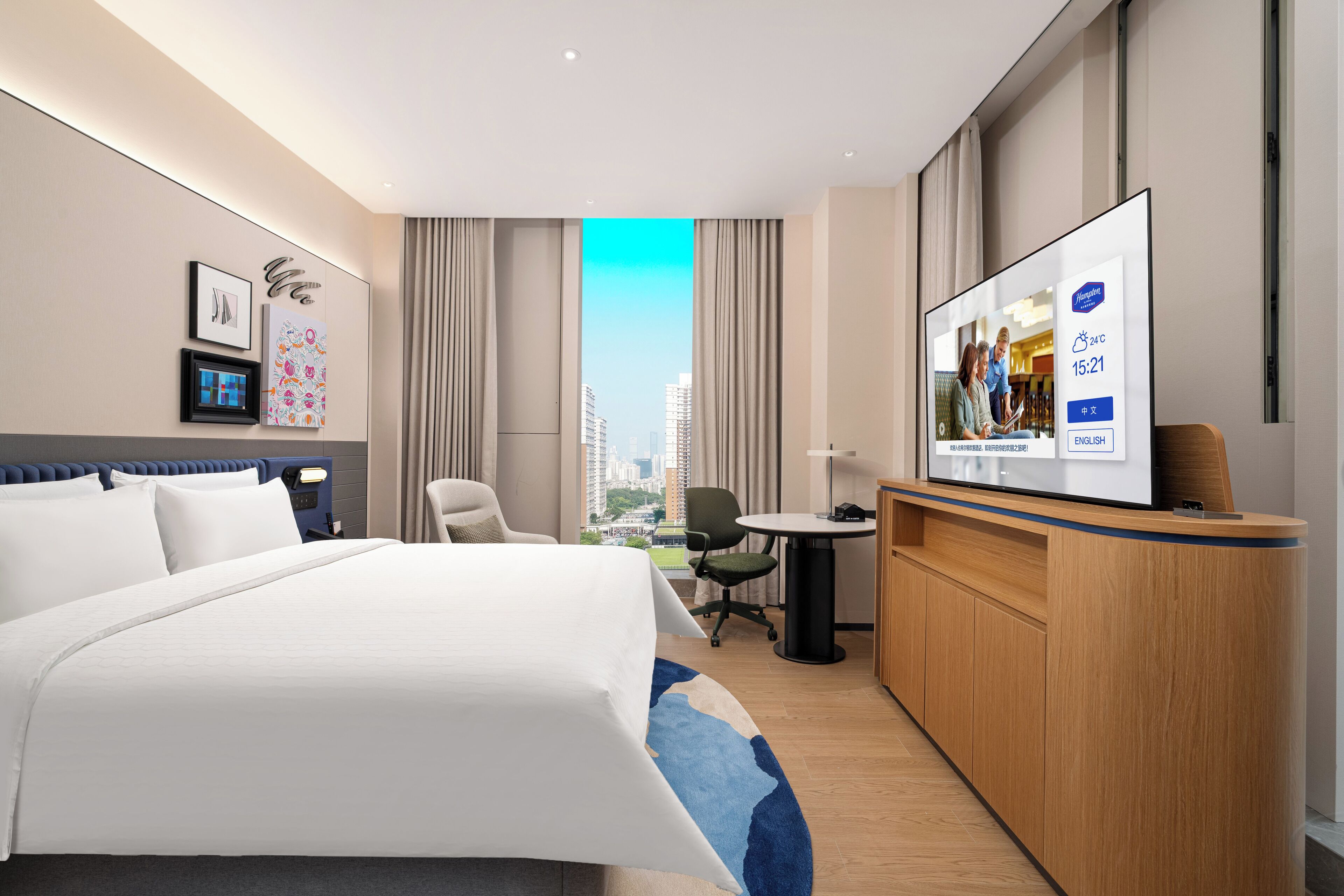 Habitación de hotel moderna con una cama grande, un escritorio, televisión y vistas a la ciudad.