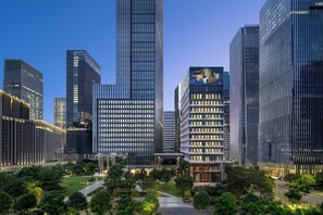 Un hôtel moderne à la façade vitrée, entouré de gratte-ciel et bordé d’un parc bien entretenu.