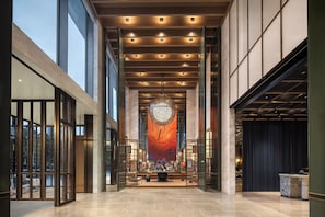 Un hall d’entrée spacieux, doté d’un plafond haut, d’un éclairage moderne et d’une pièce décorative centrale.