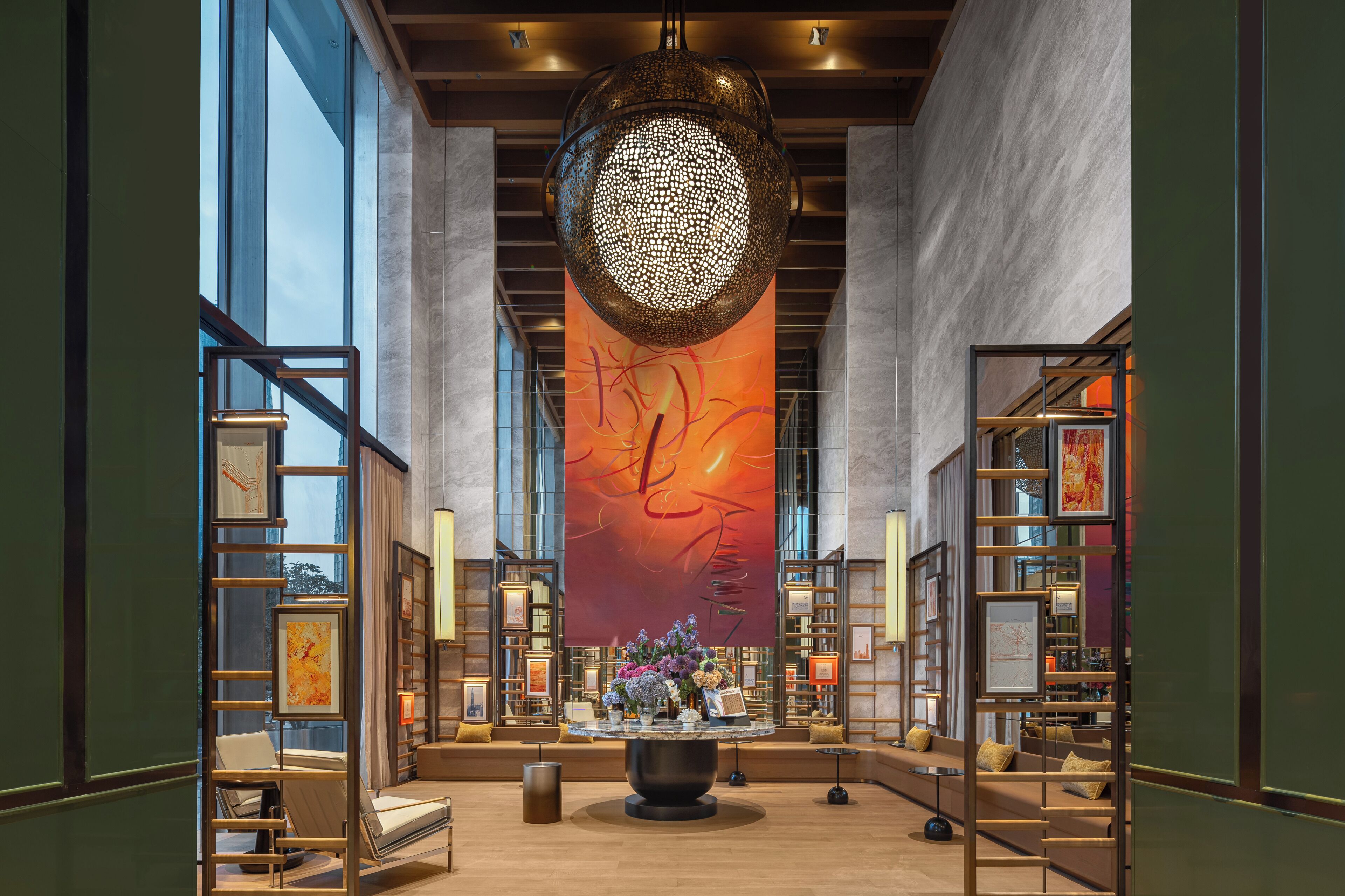 Un hall d’entrée spacieux, agrémenté d’un grand luminaire décoratif de forme circulaire, de coins salon et d’une bibliothèque.