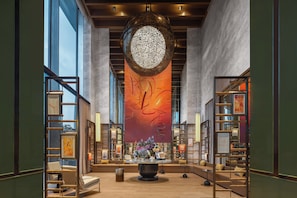 Un hall d’entrée spacieux, agrémenté d’un grand luminaire décoratif de forme circulaire, de coins salon et d’une bibliothèque.