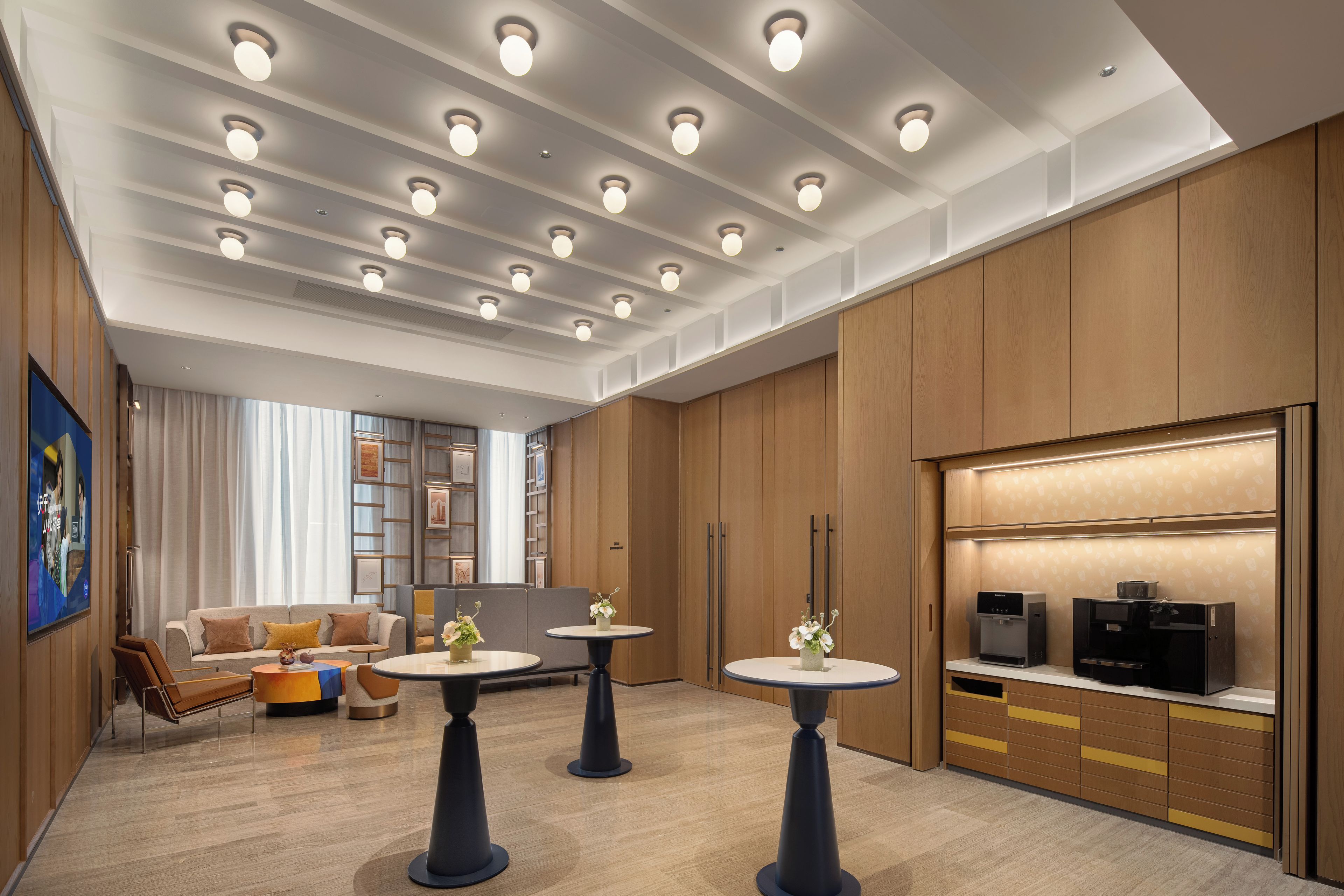 Una hall d'albergo moderna con un'area salotto, una macchina del caffè e un televisore.