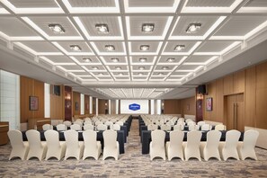 A conference room with rows of chairs, a large screen at the front, and a ceiling with recessed lighting. - Hampton by HiltonShenzhen NanshanQianhai (Shenzhen)