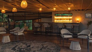 A bar area with wicker chairs, a patterned rug, and hanging lights.