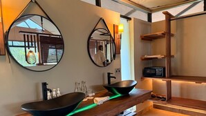 A modern bathroom with two large black sinks, wooden vanity, mirrors, and a shelf with a radio.